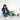 Woman sitting with a Sherpani Sedona Olivine Backpack against white background. #color_olivine-green