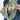 A close-up of a woman placing phone into  zipper pocket on a Sherpani Wayfarer Olivine Convertible Sling.  
