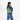 A woman wearing a Sherpani Wayfarer Olivine Convertible Sling on her back against white background.  #color_olivine-green