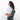 Woman wearing a Sherpani Metro Granite Anti-theft Reversible Sling on her back against white backdrop. #color_granite-grey