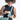 Woman placing a hand sanitizer into a Sherpani Milli Surf Blue Mini Messenger against white backdrop.  #color_surf-blue