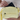 Person placing a passport inside Sherpani Skye Sol Yellow Shoulder Bag. 