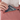 Person placing a passport inside Sherpani Zoom Desert Pink Slim RFID Crossbody.