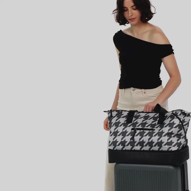 A Woman shows different ways to wear a Sherpani Boston Houndstooth Anti-theft Weekender, including on a suitcase. 