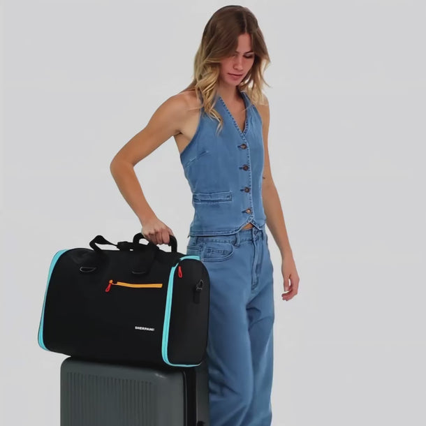 A Woman shows features of a Sherpani Jaunt Chromatic Black Garment Duffle, such as the different strap options. 