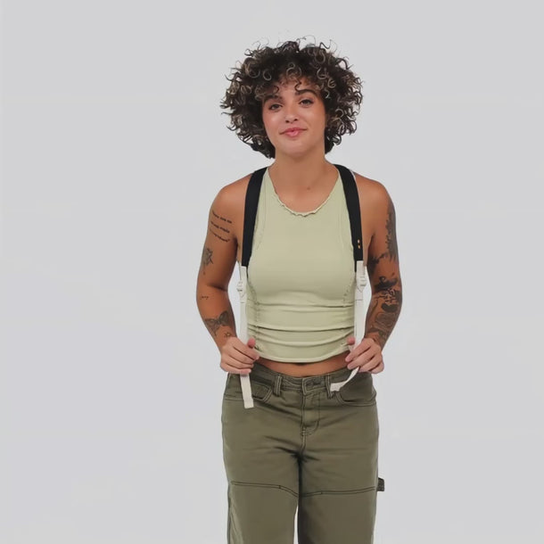 A Woman shows the transition of the Sherpani Wayfarer Terrazzo Print Convertible Sling from a backpack to a sling bag.