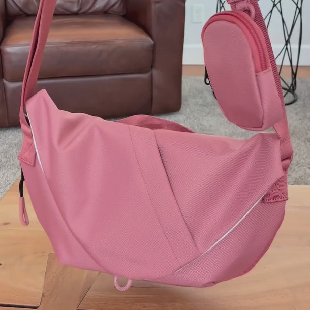 A woman packs a water bottle into the Sherpani Mina Desert Pink Medium Crossbody Bag water bottle pocket. 