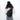 Woman wearing a Sherpani Esprit Raven Black Sling on her back against white backdrop. #color_raven-black