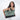 A woman holding a Sherpani Boston Aloe Mist Green Anti-theft Weekender against a white background. #color_aloe-mist-green